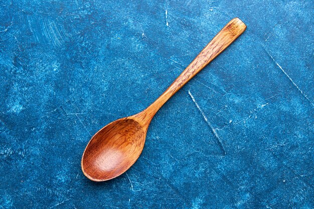 Top view wooden spoon on blue table with copy place