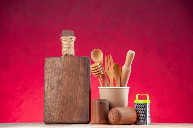Top view of wooden spoon in an empty plastic coffee pot cutting board grater on pink surface