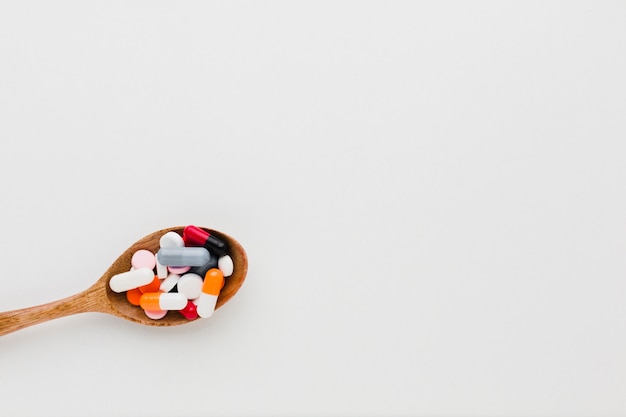 Top view wooden spoon filled with pills and copy space
