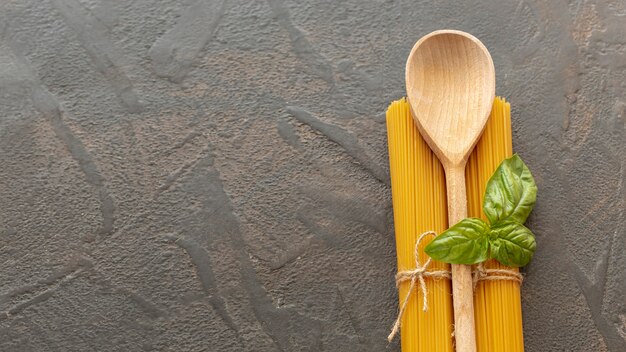 Top view of wooden spoon and spaghetti with copy space