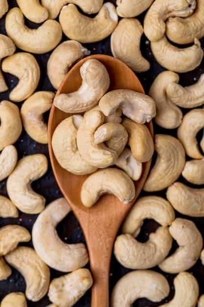 Top view of a wooden spoon with cashew on black background