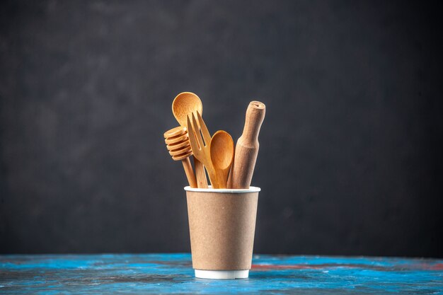 Top view of wooden spoons in an empty plastic coffee pot on blue surface