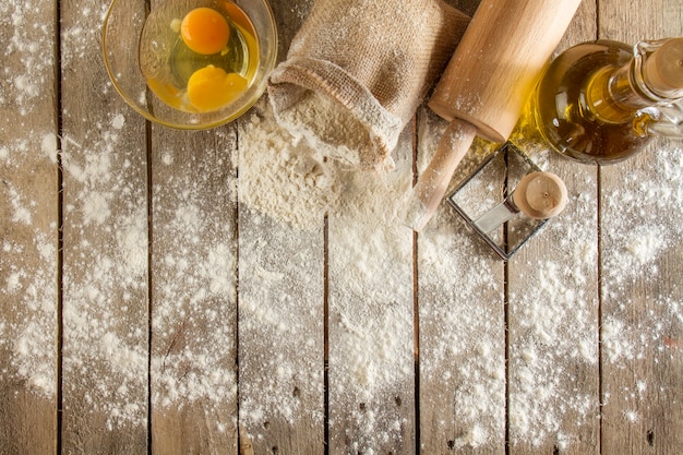 小麦粉、卵、麺棒で木製の表面の平面図