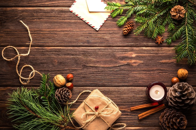 Top view of a wooden table decorated with pine tree branches and candles for Christmas