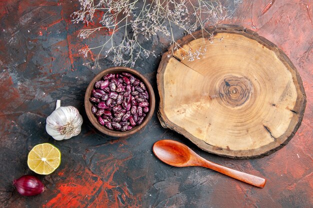 Top view of wooden tray beans garlic onion lemon and spoon on mixed color background