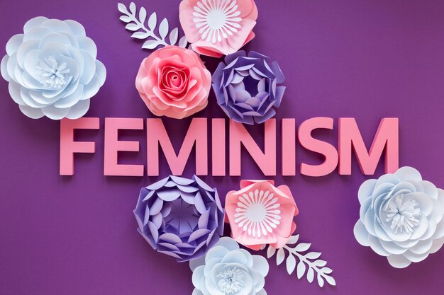 Top view of the word feminism with paper flowers for women's day