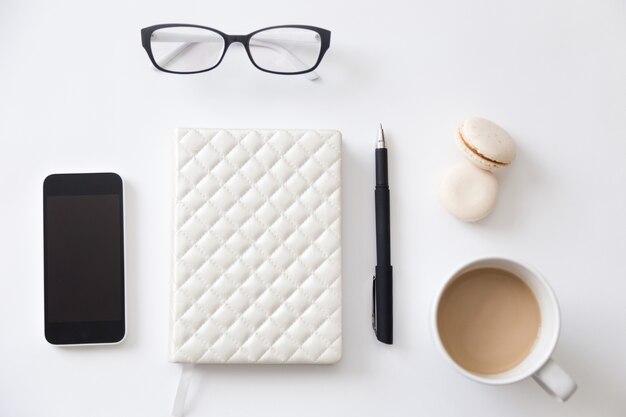 Top view of a working desk with notebook, phone, coffee