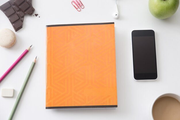 Top view of a working desk with orange notebook