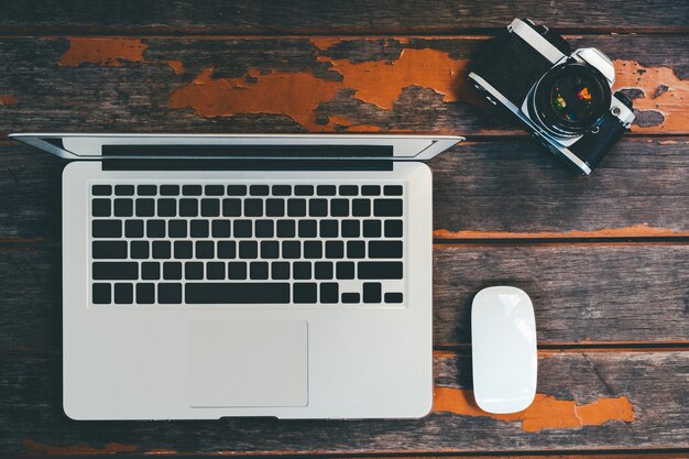 top view of working table with laptop and camera on wooden background