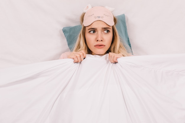 Top view of worried blonde woman in sleep mask