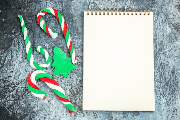 Top view xmas candies a notepad on grey surface