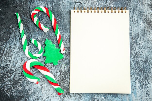 Top view xmas candies a notepad on grey surface