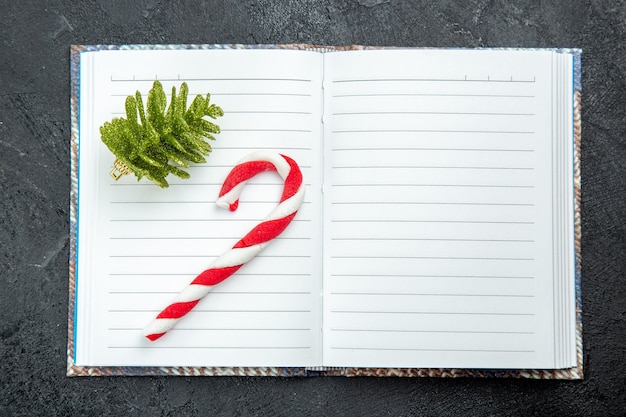 Top view a xmas candy and xmas tree toy on opened notebook on dark surface