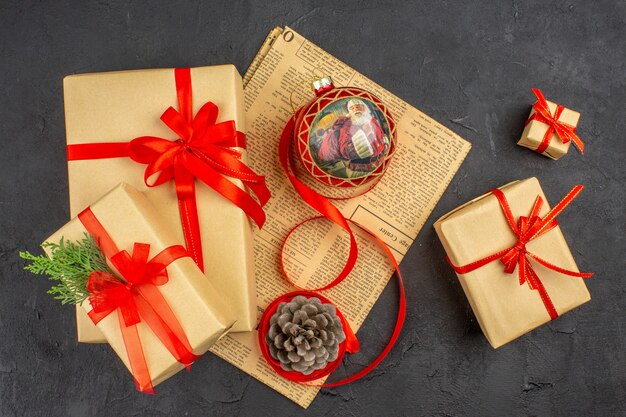 Top view xmas gift in brown paper ribbon xmas tree toy on newspaper on dark surface