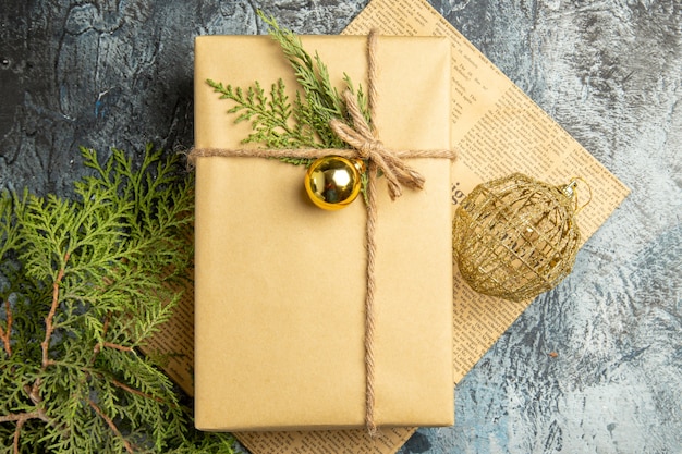 top view xmas gift on newspaper pine branches xmas toy on grey surface