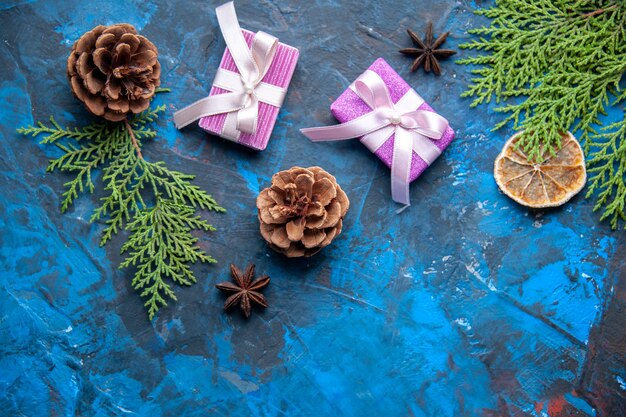 Top view xmas gifts fir tree branches cones anises on blue background free place