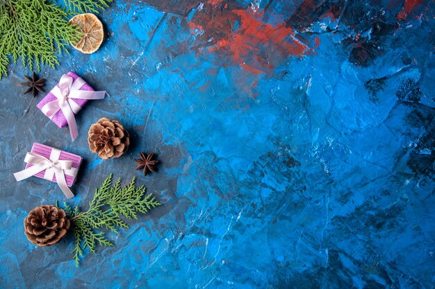 Top view xmas gifts fir tree branches cones anises on blue surface