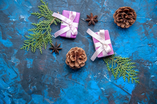 Top view xmas gifts fir tree branches cones anises on blue surface