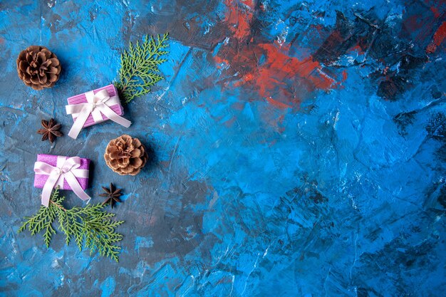 Top view xmas gifts fir tree branches cones anises on blue surface