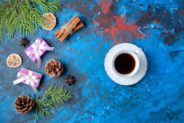 Free photo top view xmas gifts fir tree branches cones anises cup of tea on blue background free place