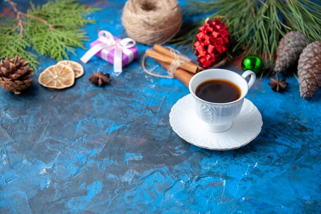 Top view xmas gifts fir tree branches cones anises a cup of tea on blue surface