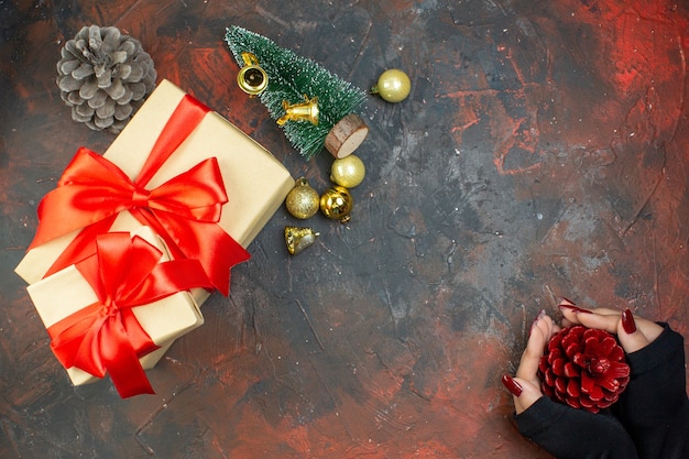 어두운 빨간색 테이블 복사 공간에 여자 손에 상위 뷰 크리스마스 선물 황금 크리스마스 공 선물