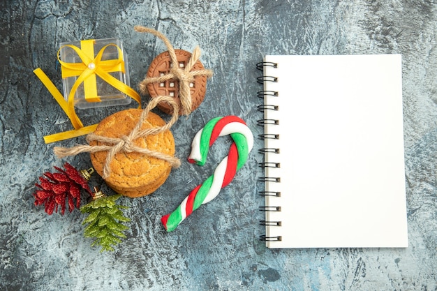 Free photo top view xmas gifts tied cookies xmas candies a notebook on grey surface