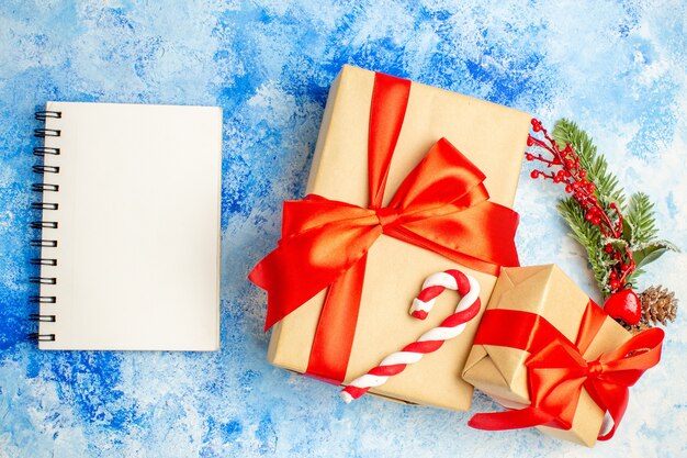 Top view xmas gifts tied with red bow notepad on blue table