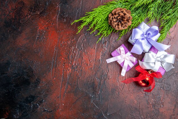 Top view xmas gifts tree branches with cone xmas tree toy on dark red surface