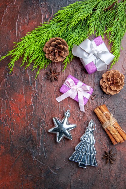 Foto gratuita regali di natale vista dall'alto con scatola rosa e ramo di albero di nastro bianco anice cannella giocattoli di albero di natale su superficie rosso scuro