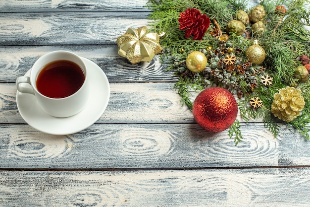 Top view xmas ornnaments a cup of tea fir tree branches on wooden background free space