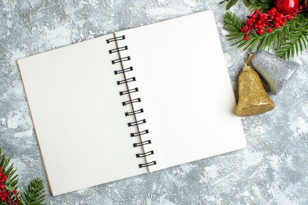 Top view xmas red berry xmas bells on notepad on grey white table