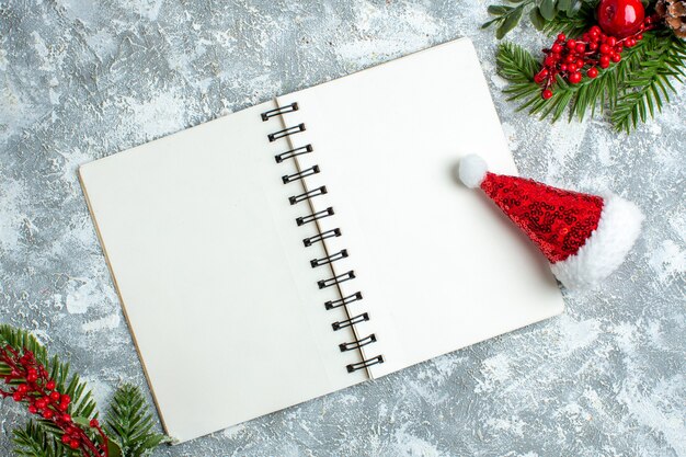 Top view xmas red berry xmas hat notepad on grey white table