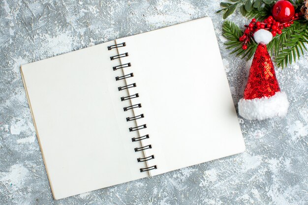 Top view xmas red berry xmas hat notepad on grey white table
