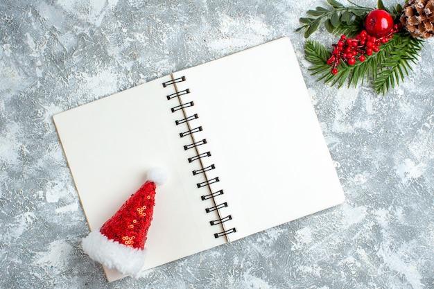 Top view xmas red berry xmas hat on notepad on grey white table