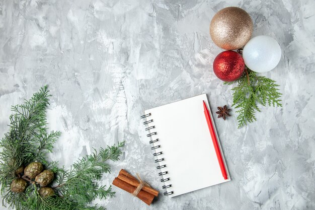 Top view xmas tree balls notebook pencil cinnamon sticks on grey surface