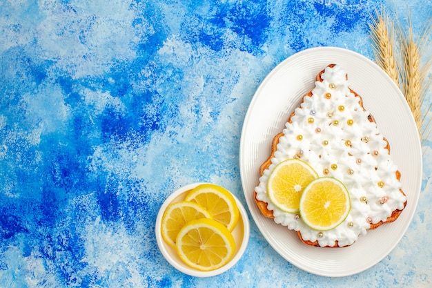 여유 공간이 있는 파란색 테이블에 있는 접시 레몬 조각에 상위 뷰 크리스마스 트리 케이크