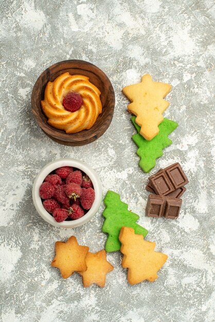 Top view xmas tree cookies biscuit in bowl bowl with raspberries on grey table