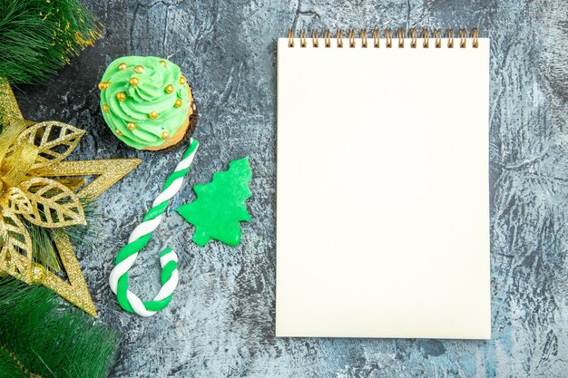 Top view xmas tree cupcake xmas candy xmas ornaments a notebook on grey background