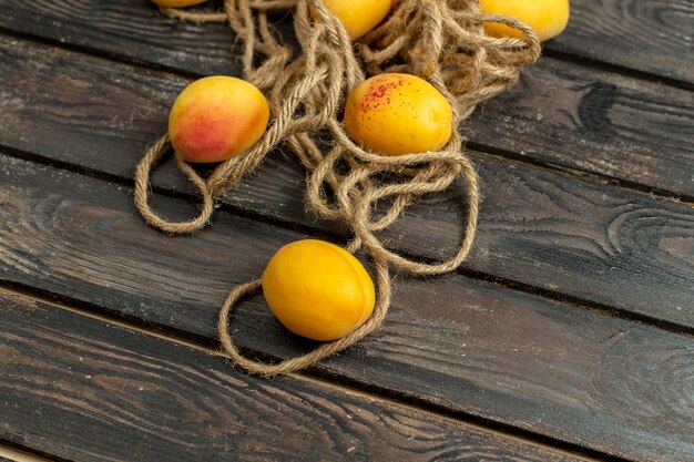 Top view yellow apricots mellow and fresh fruits on the brown rustic background