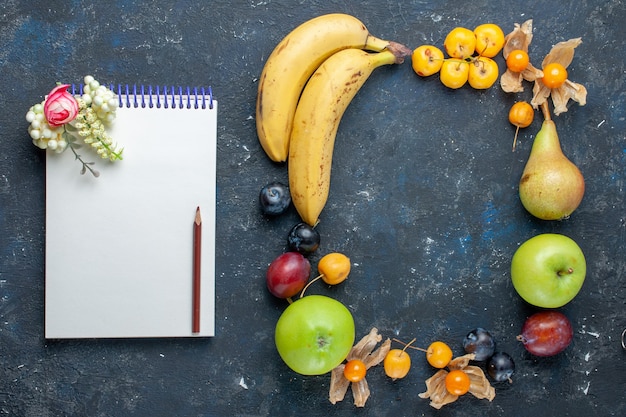 Top view yellow bananas with fresh green apples notepad pears plums and sweet cherries on the dark desk vitamine fruit berry health