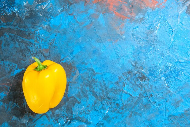 Top view of yellow bell-pepper on blue surface