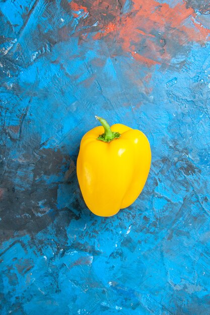 Top view of yellow bell-pepper on blue surface