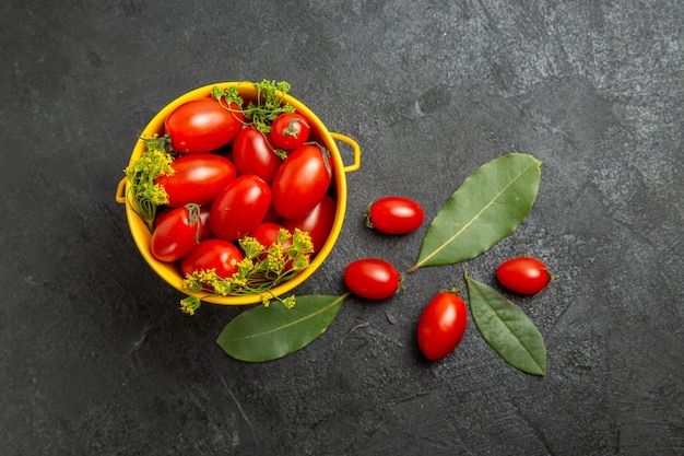 Top view yellow bucket of cherry tomatoes and dill flowers and bay leaves on the dark ground with copy space