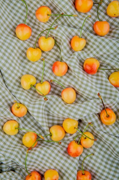 Top view of yellow cherries on plaid cloth table