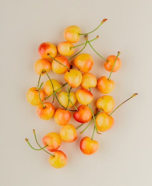 Top view of yellow cherries on white surface