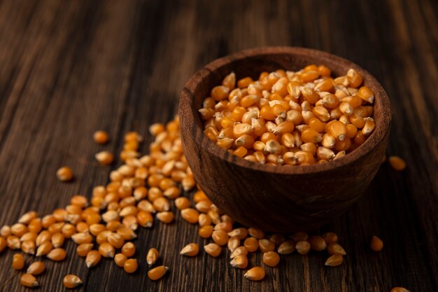 Top view of yellow corn kernels on a wooden bowl with kernels isolated on a wooden table