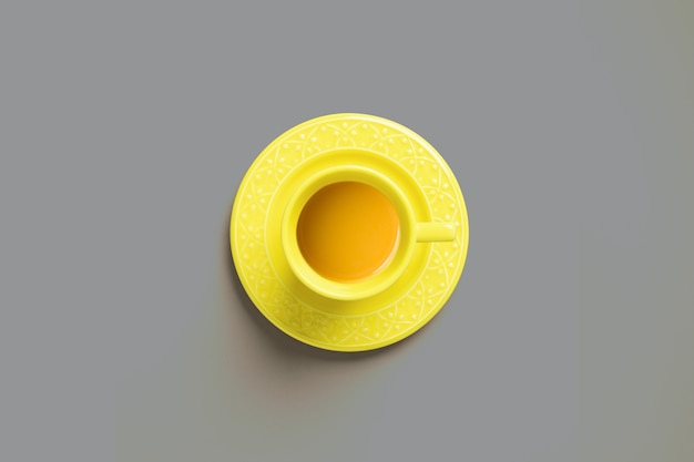Top view of a yellow cup of tea on gray