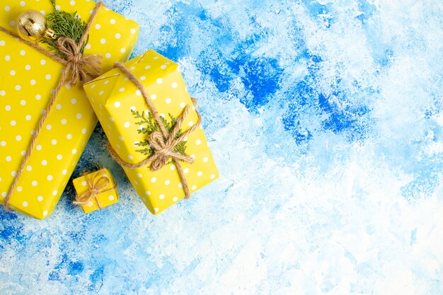 Top view yellow gifts tied with rope on blue table with free space