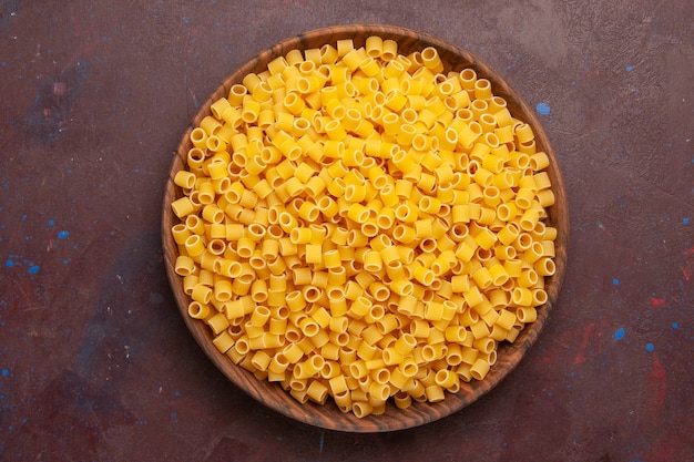 Top view yellow italian pasta raw little formed on dark background pasta food raw meal dough